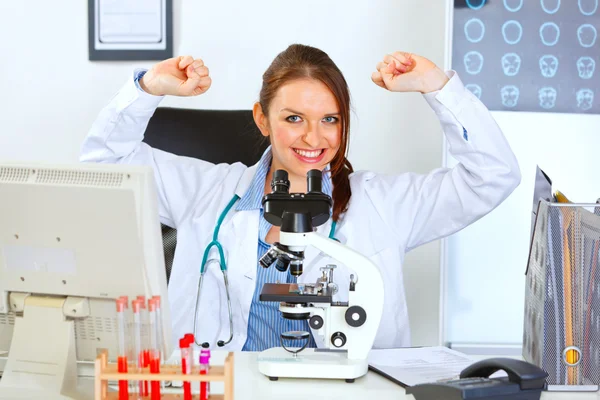 Lachende vrouwelijke arts zitten in laboratorium en rejoicin — Stockfoto