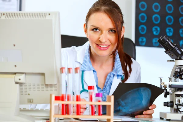 Kobieta szczęśliwa lekarz siedzi przy stole biuro — Zdjęcie stockowe