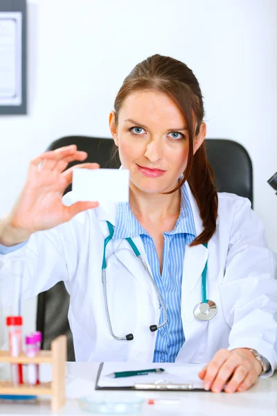 Mujer doctora autorizada sentada en la mesa del consultorio y sosteniendo b — Foto de Stock