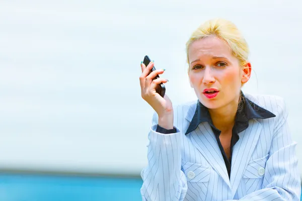 Outraged business woman with cell phone leaning on railing at of — Stock Photo, Image
