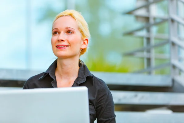 Smiling business woman sitting on stairs at office building — Stock Photo, Image