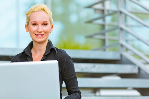 Pleased business woman sitting on stairs at office building — Stock Photo, Image