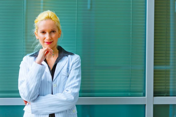 Nadenkend zakenvrouw met hand in de buurt van gezicht staande in de buurt van office — Stockfoto