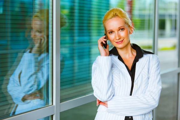 Smiling business woman talking on mobile at office building — Stock Photo, Image
