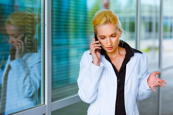 Concentrated business woman talking on mobile at office building — Stock Photo, Image