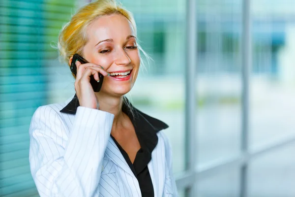 Smiling business woman talking on mobile at office building — Stock Photo, Image