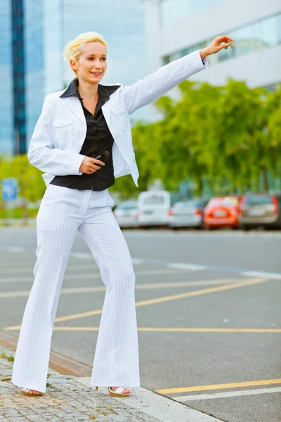 Lächelnde Geschäftsfrau erwischt Taxi in der Nähe von Bürozentrum — Stockfoto