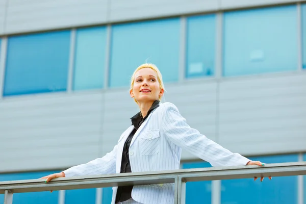Mujer de negocios sonriente apoyada en barandilla en el edificio de oficinas — Foto de Stock