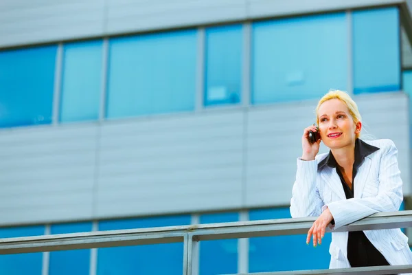 Деловая женщина, опирающаяся на перила в офисном здании и разговаривающая — стоковое фото