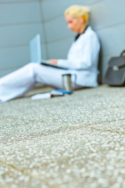 Podnikání žena pracující na podlaze na kancelářské budovy v pozadí — Stock fotografie
