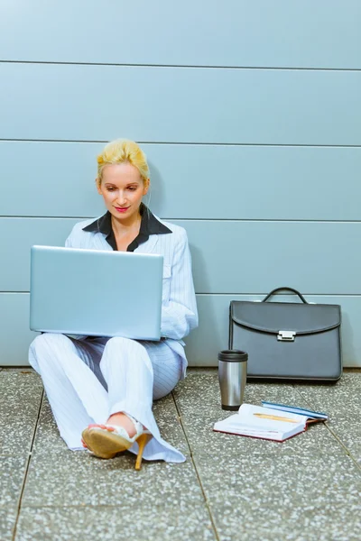 Geconcentreerde zakenvrouw zittend op de vloer op kantoorgebouw — Stockfoto