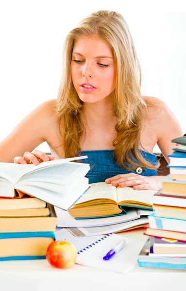 Concentrated teen girl sitting at table and searching in books — Stock Photo, Image