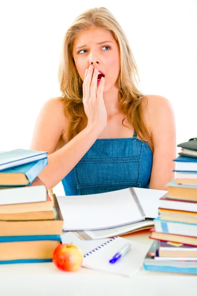 Shocked teen girl sitting at desk with piles of books — Stock Photo, Image