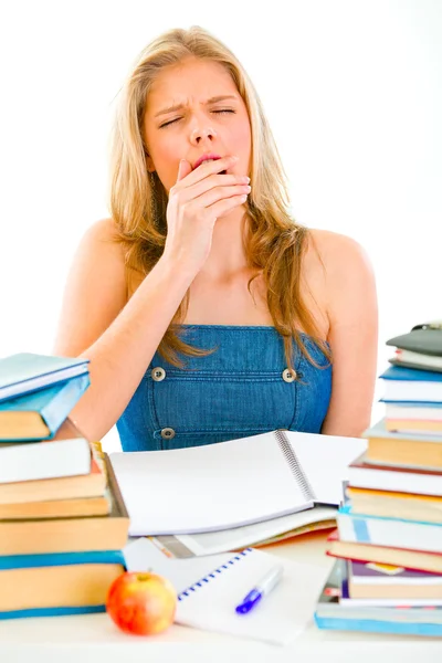 stock image Yawning tired teengirl sitting at table with piles of books