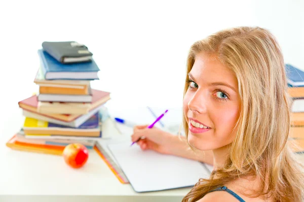 微笑着坐在桌前和做功课的 teengirl — 图库照片