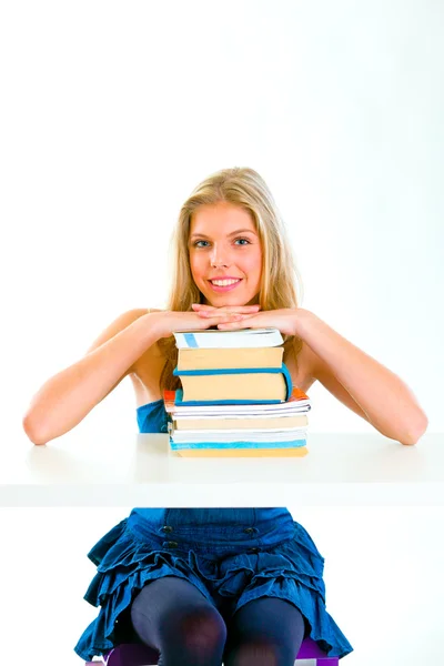 Lachende jong meisje zit aan Bureau en hand in hand op stapels boeken — Stockfoto