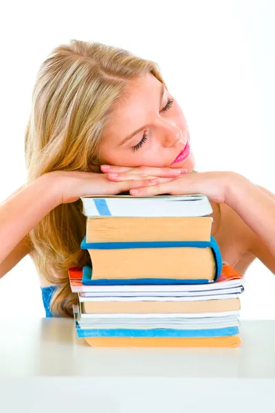 Trött tjej sitter vid skrivbord och sova på högar av böcker — Stockfoto