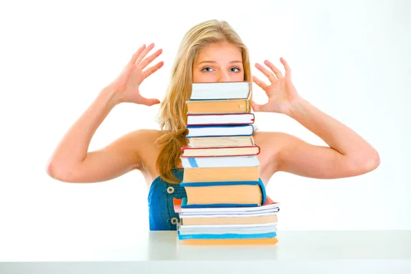 Sitting at table stressed teen girl looking out of pile of book — Stock Photo, Image