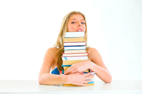 Sentado en la mesa adolescente chica abrazando pila de libros y mirando hacia fuera — Foto de Stock