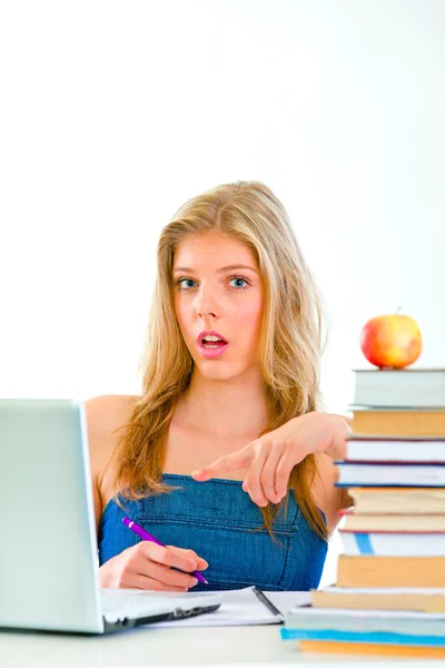Chica adolescente curiosa sentada en la mesa con libros y señalando en la —  Fotos de Stock