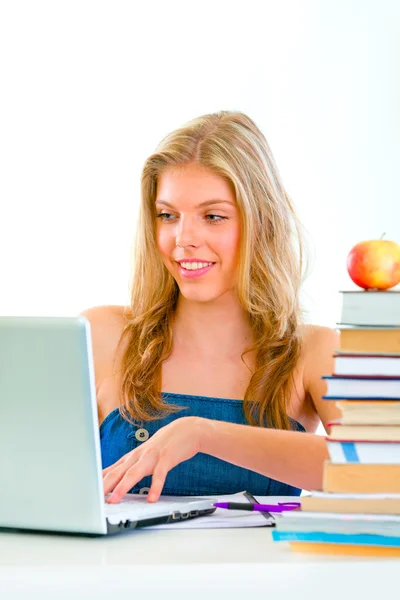 Smiling beautiful girl sitting at table and working on laptop — Stock Photo, Image