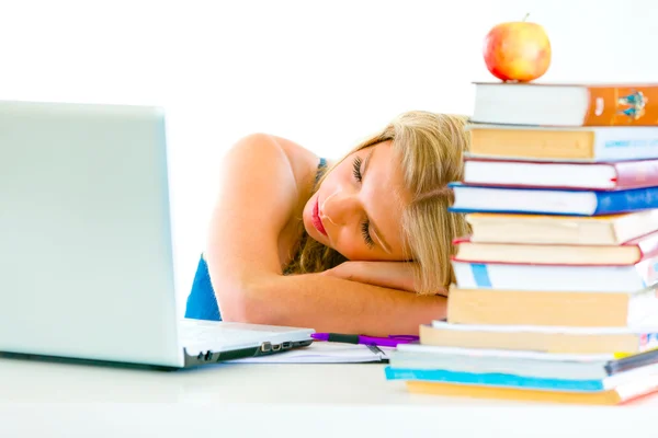 Tired young girl sleeping on table with books and laptop — Stock Photo, Image
