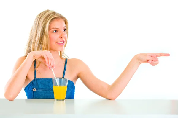 Cheerful teenager with orange juice pointing in corner — Stock Photo, Image