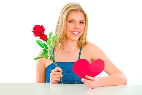 Härlig flicka sitter vid bord med rose och valentine hjärta — Stockfoto