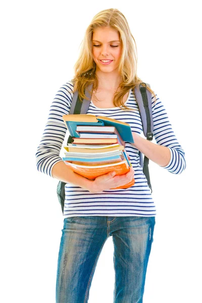 Lächelndes Teenie-Mädchen mit einem Stapel Schulbücher in der Hand beim Lesen — Stockfoto