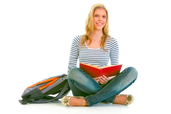 Sorrindo menina adolescente com mochila sentada no chão e lendo sch — Fotografia de Stock