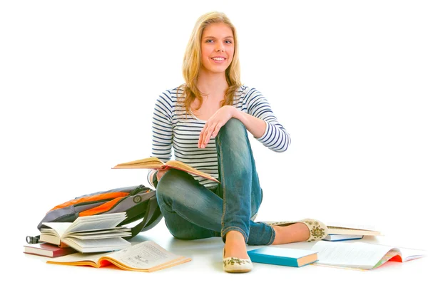 Veselou mladistvou dívku sedící na podlaze mezi učebnice — Stock fotografie