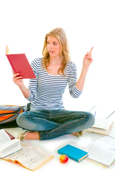 Pensive teenager sitting on floor among schoolbooks and studying — Stock Photo, Image
