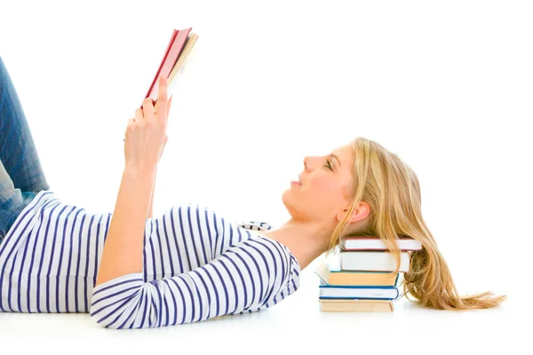 Liggande på golvet teengirl med att vila huvudet på högen av skolböcker läsning — Stockfoto