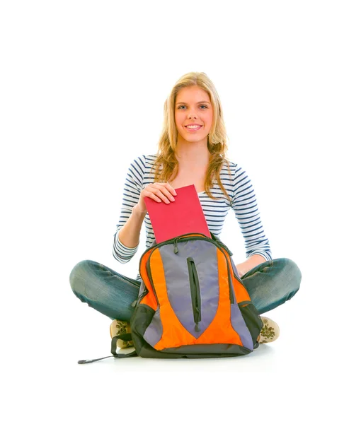 Sentado no chão feliz adolescente recebendo livro de saco escolar — Fotografia de Stock