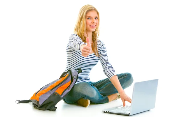 Sentado en el suelo con la mochila y el ordenador portátil teengirl sonriente mostrando los pulgares — Foto de Stock