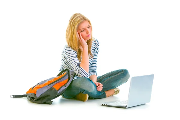 Κουρασμένος έφηβος κορίτσι που κάθεται στο πάτωμα με σακίδιο και ψάχνετε για φορητό υπολογιστή — Φωτογραφία Αρχείου