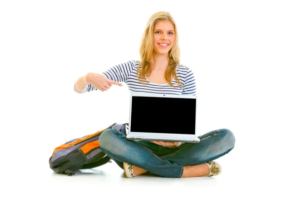 Adolescente sorrindo sentado no chão com saco escolar e apontando o dedo no colo — Fotografia de Stock