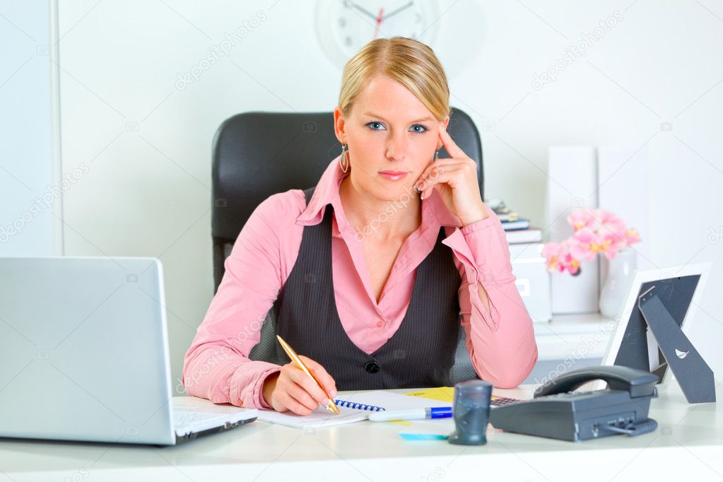 Portrait of serious modern business woman sitting at office desk