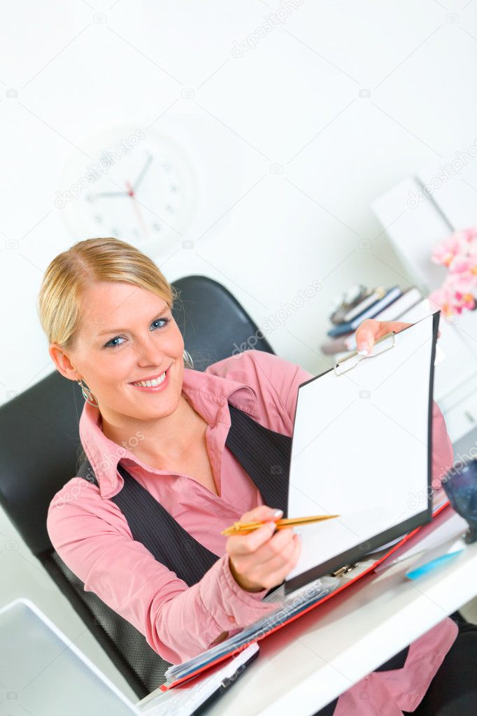 Smiling business woman sitting at office desk with document