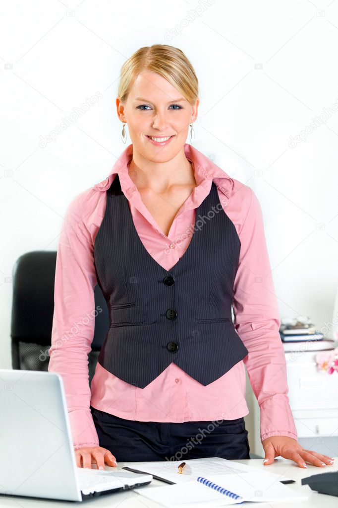 Friendly business woman standing near office desk