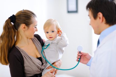 Cute baby on mamas hand playing with stethoscope clipart