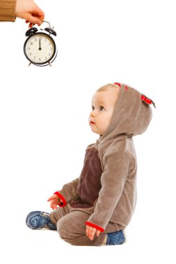 Cute baby in costume of Santa Claus's reindeer looking on alarm clipart