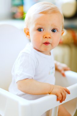Eat smeared pretty baby in baby chair interestedly looking clipart