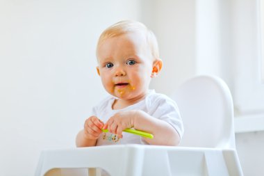 Eat smeared lovely baby with spoon in hand clipart