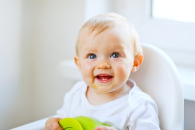 Lovely baby girl sitting in baby chair clipart