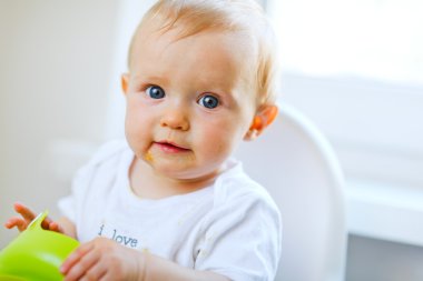 Cheerful baby girl sitting in baby chair clipart