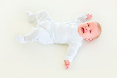 Crying four month old baby laying on back clipart