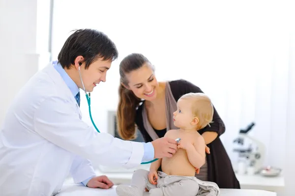 Bebé sorprendido siendo examinado por un médico usando un estetoscopio — Foto de Stock