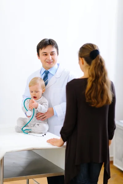 Pediatra conversando com a mãe enquanto bebê brincando com Stethos — Fotografia de Stock