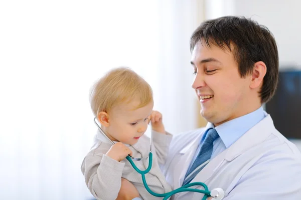 Portrait of happy cute baby with stethoscope on hands of pediatr — Stock Photo, Image